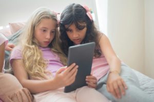 Young girls gaze into digital tablet. Photo by Kampus Production on Pexels.